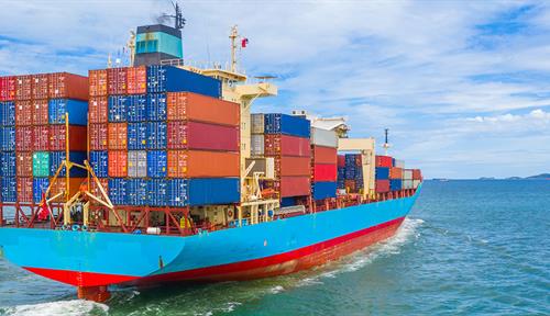 Photograph of a loaded container ship moving through the water.