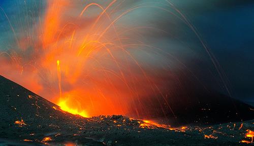 Photo shows orange lava spewing from atop a volcanic crater.